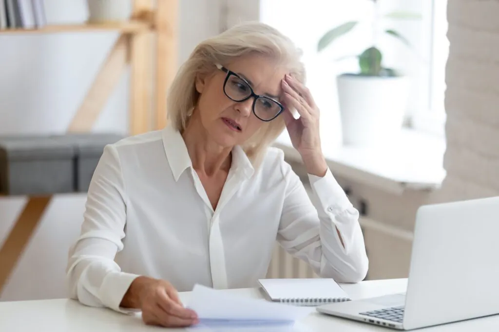 Concerned woman reviewing documents at laptop